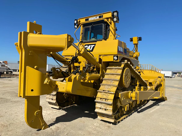 Close-up of a sturdy bulldozer blade pushing earth on a sunny day