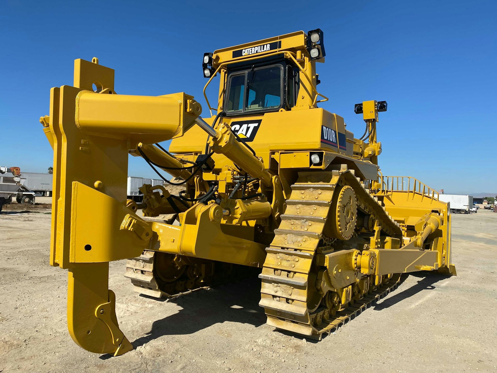 A powerful yellow munck truck lifting heavy equipment at a construction site under a clear blue sky.