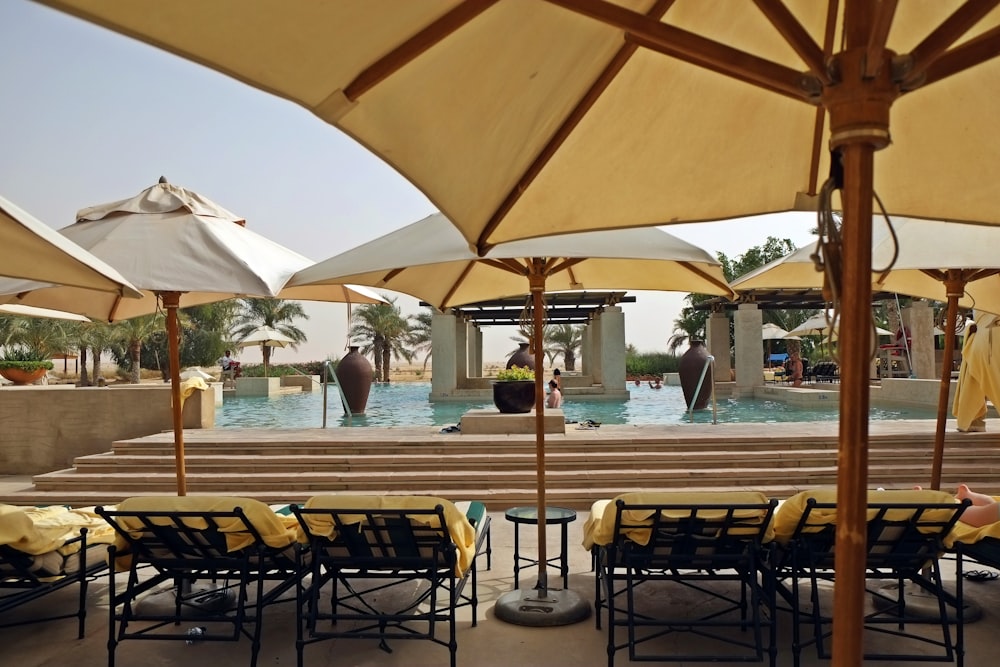 a group of tables and chairs with umbrellas over them