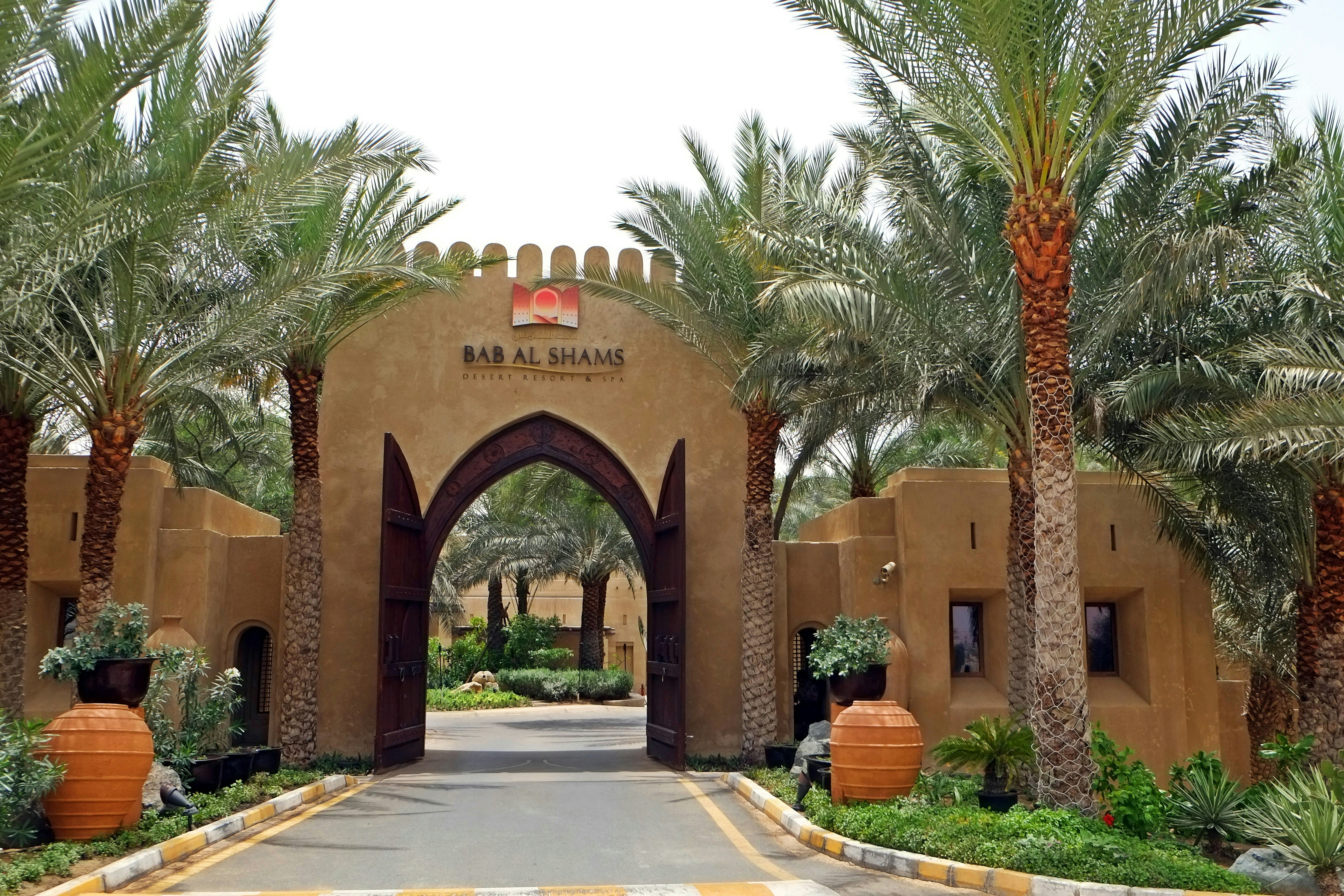 the entrance to a resort surrounded by palm trees