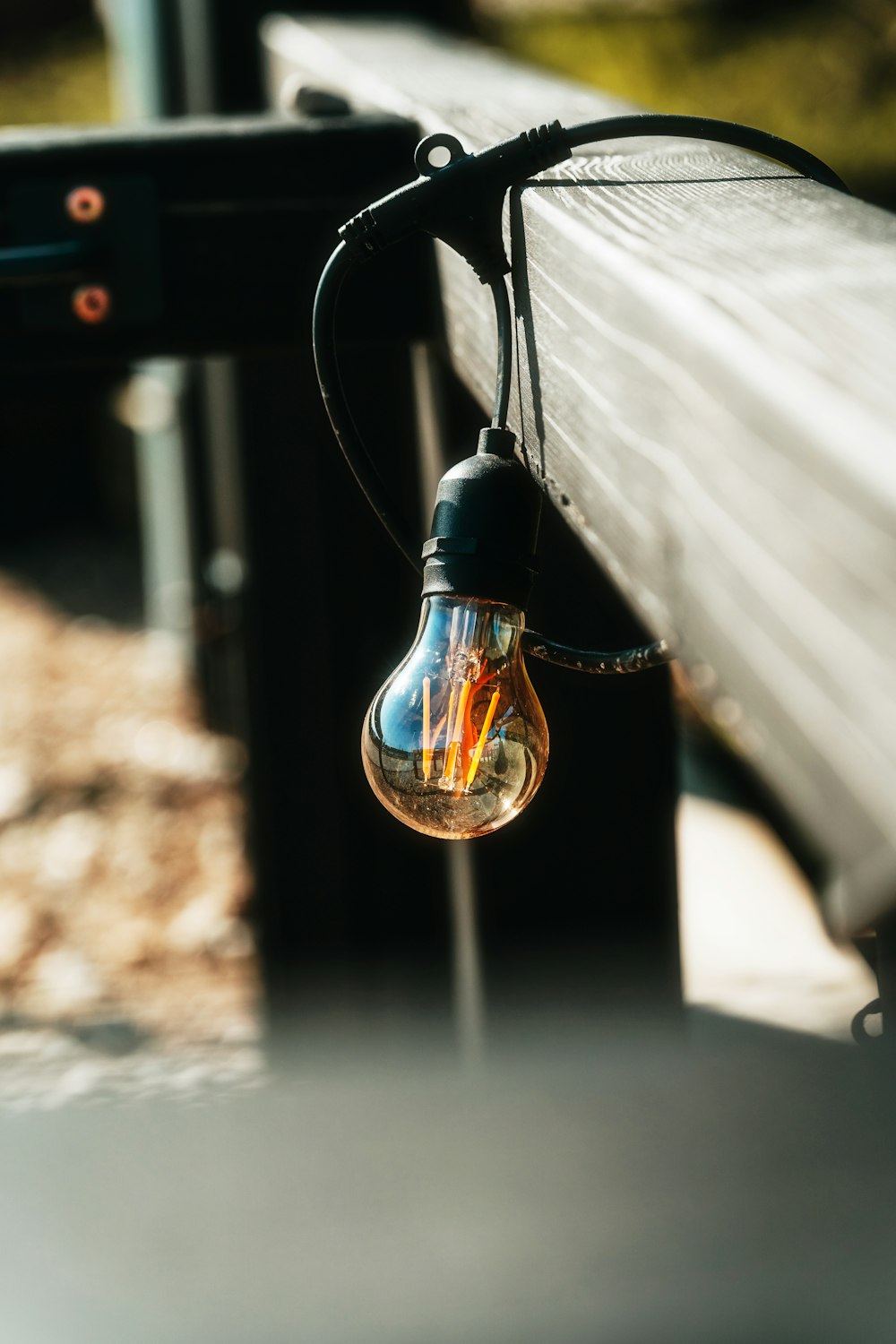 a light bulb hanging from the side of a wooden bench