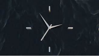 Minimalist digital clock with sharp edges softly illuminated with purple neon accents on a deep charcoal background.