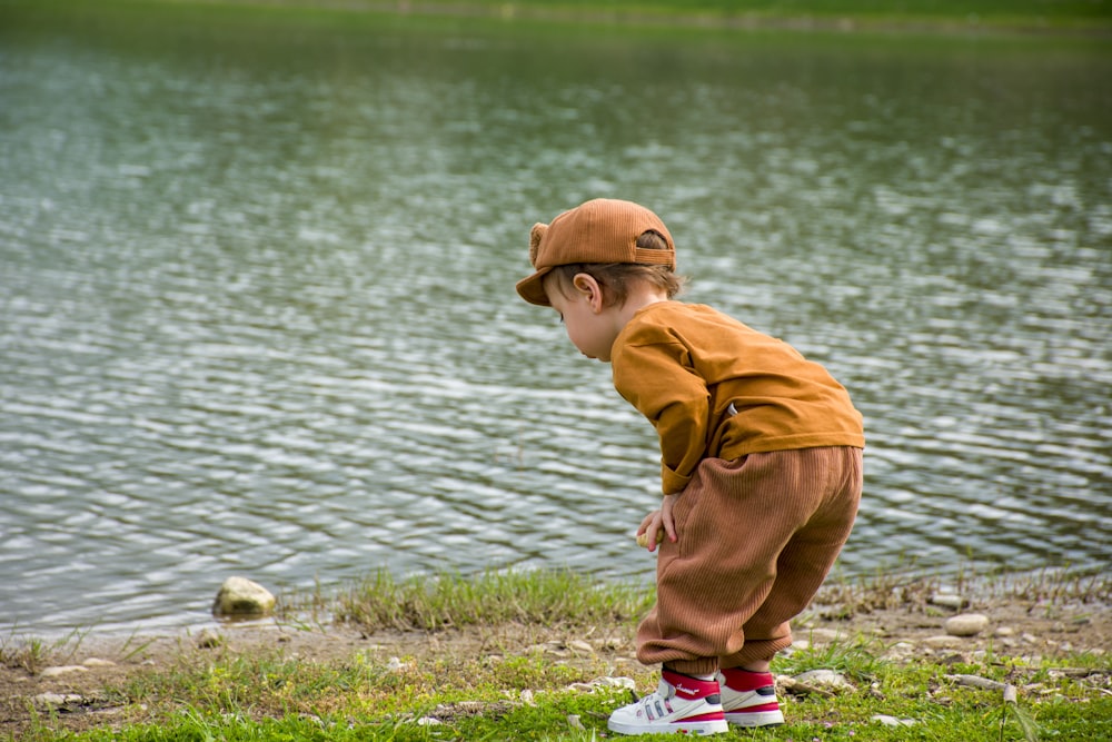 a little boy standing next to a body of water