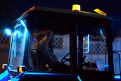 An owner-operator reviewing load details on a tablet inside a truck cabin with ambient blue lighting.