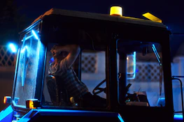 An owner-operator reviewing load details on a tablet inside a truck cabin with ambient blue lighting.