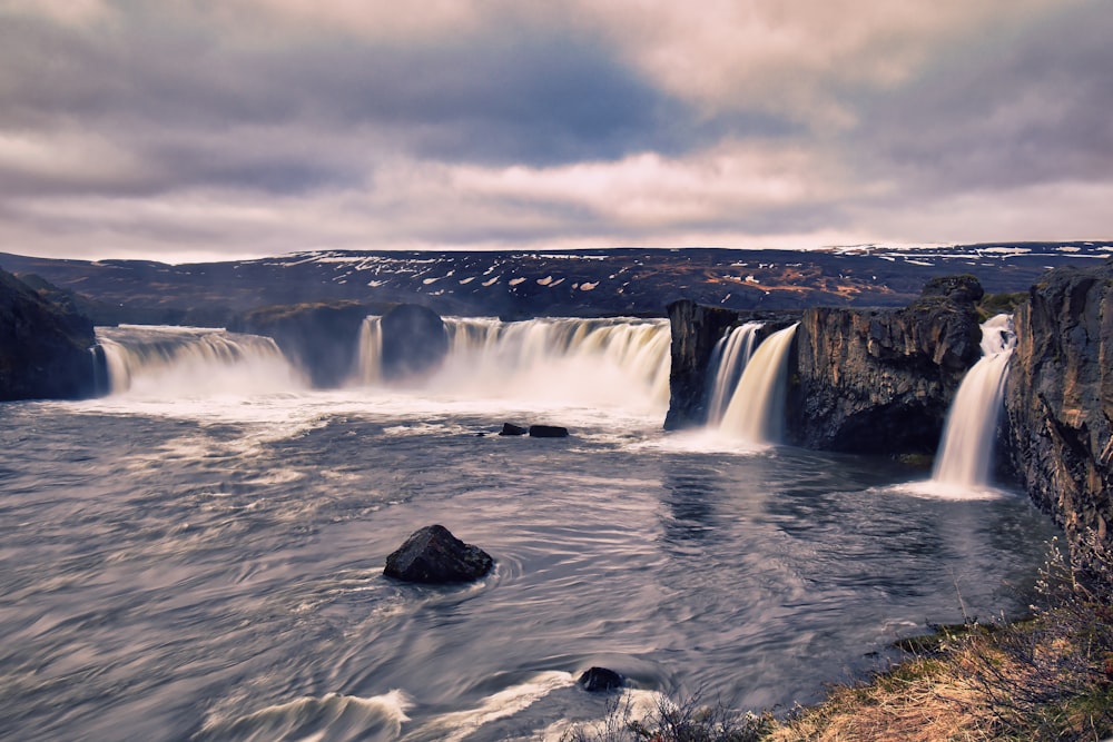 a large waterfall with a man standing on top of it