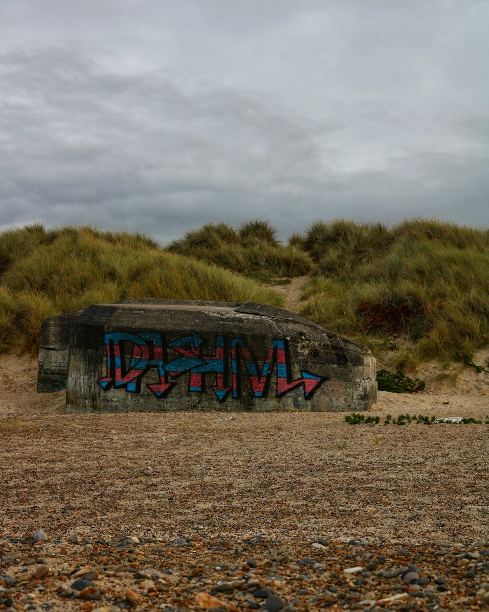 a rock covered in graffiti sitting on top of a sandy beach