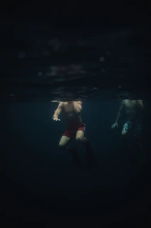 A swimmer slicing through dark water illuminated by neon blue pool lights