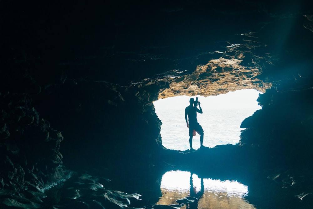 Un hombre parado en una cueva mirando el agua