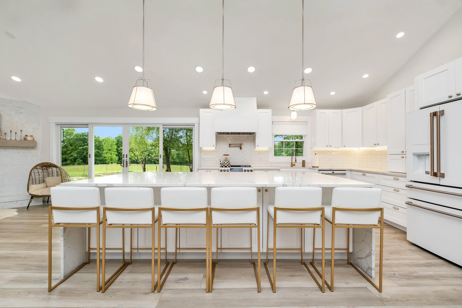 A bright, renovated kitchen with a large marble island and white cabinetry.