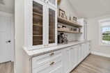 a kitchen with white cabinets and wood floors