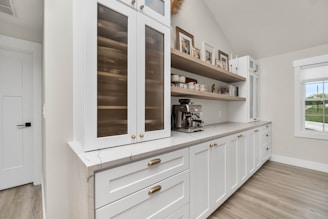 a kitchen with white cabinets and wood floors