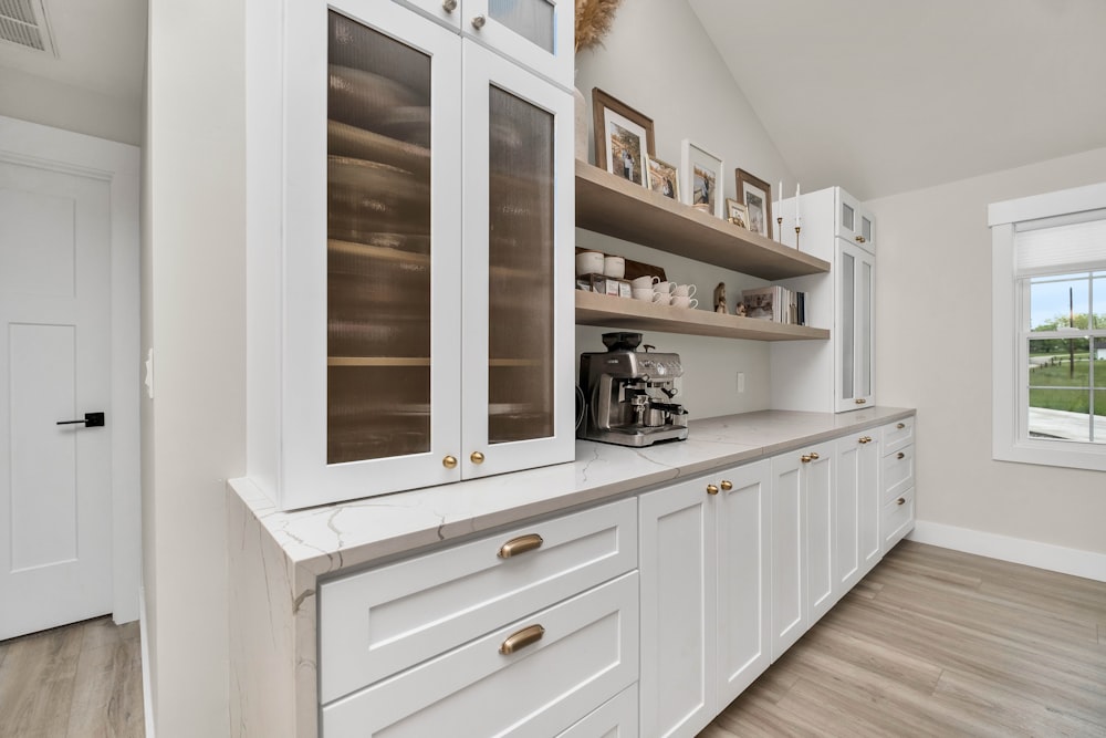 une cuisine avec des armoires blanches et des planchers de bois