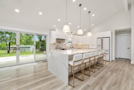 a large kitchen with a center island and marble counter tops