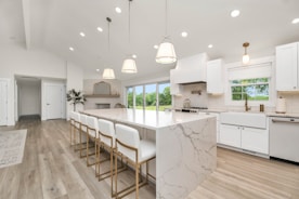 a large kitchen with a marble island and white cabinets