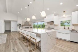 a large kitchen with a marble island and white cabinets