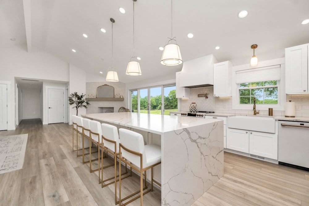 a large kitchen with a marble island and white cabinets