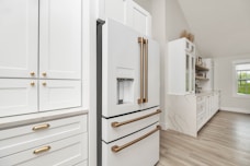 a kitchen with white cabinets and gold handles
