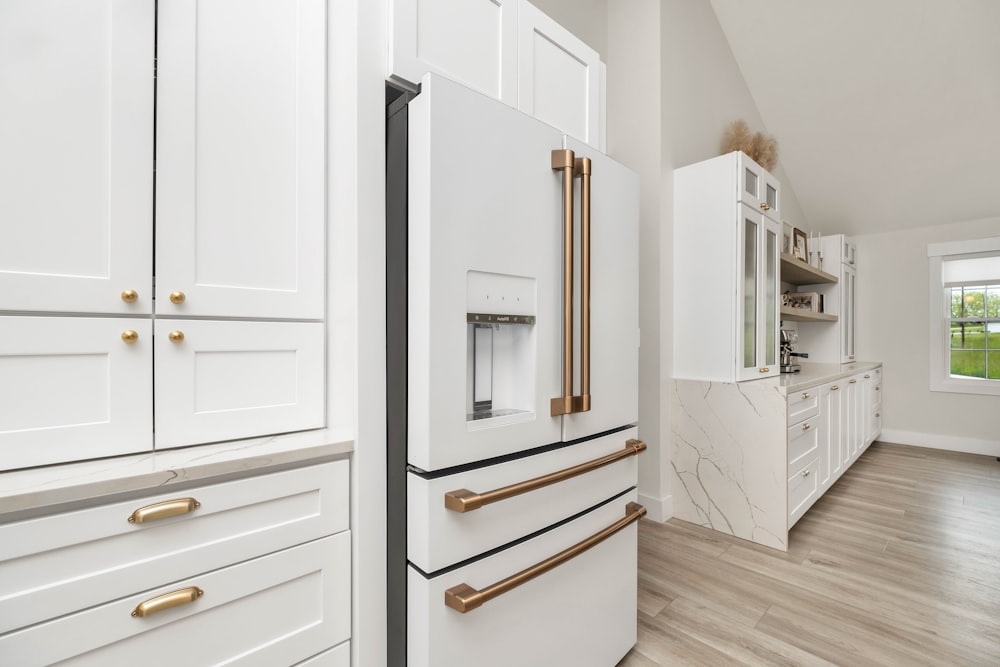 a kitchen with white cabinets and gold handles