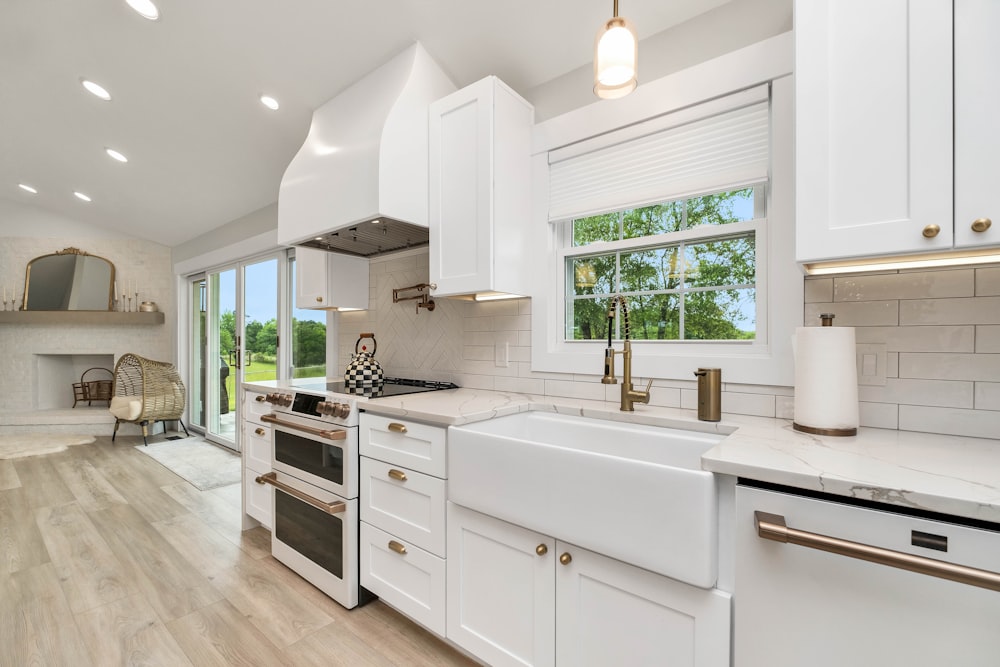 a kitchen with white cabinets and a large window