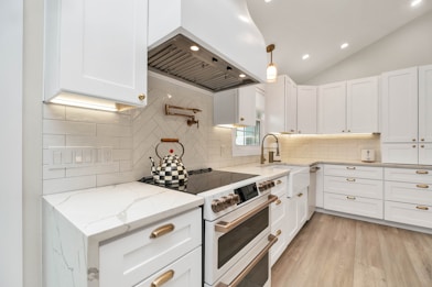 a kitchen with white cabinets and a stove top oven