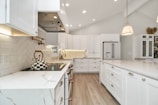 a kitchen with white cabinets and marble counter tops
