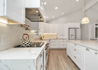 a kitchen with white cabinets and marble counter tops