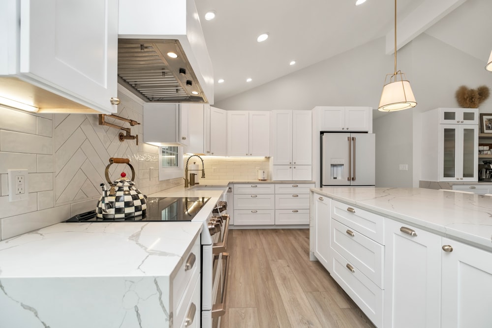 a kitchen with white cabinets and marble counter tops