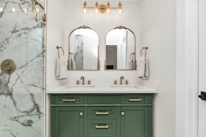 Farmhouse modern bathroom with marble counter tops and green cabinets