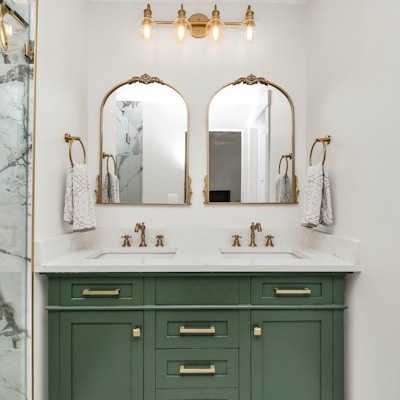 a bathroom with marble counter tops and green cabinets