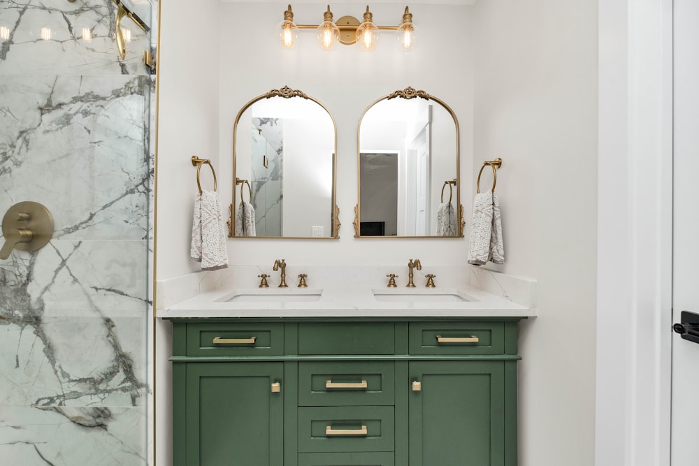 a bathroom with marble counter tops and green cabinets