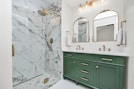 a bathroom with green cabinets and a marble shower