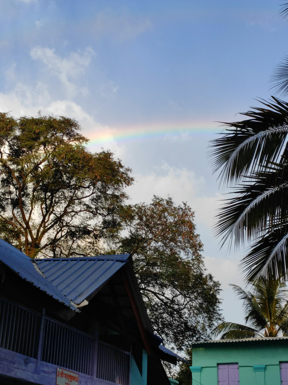 a rainbow shines in the sky over a house