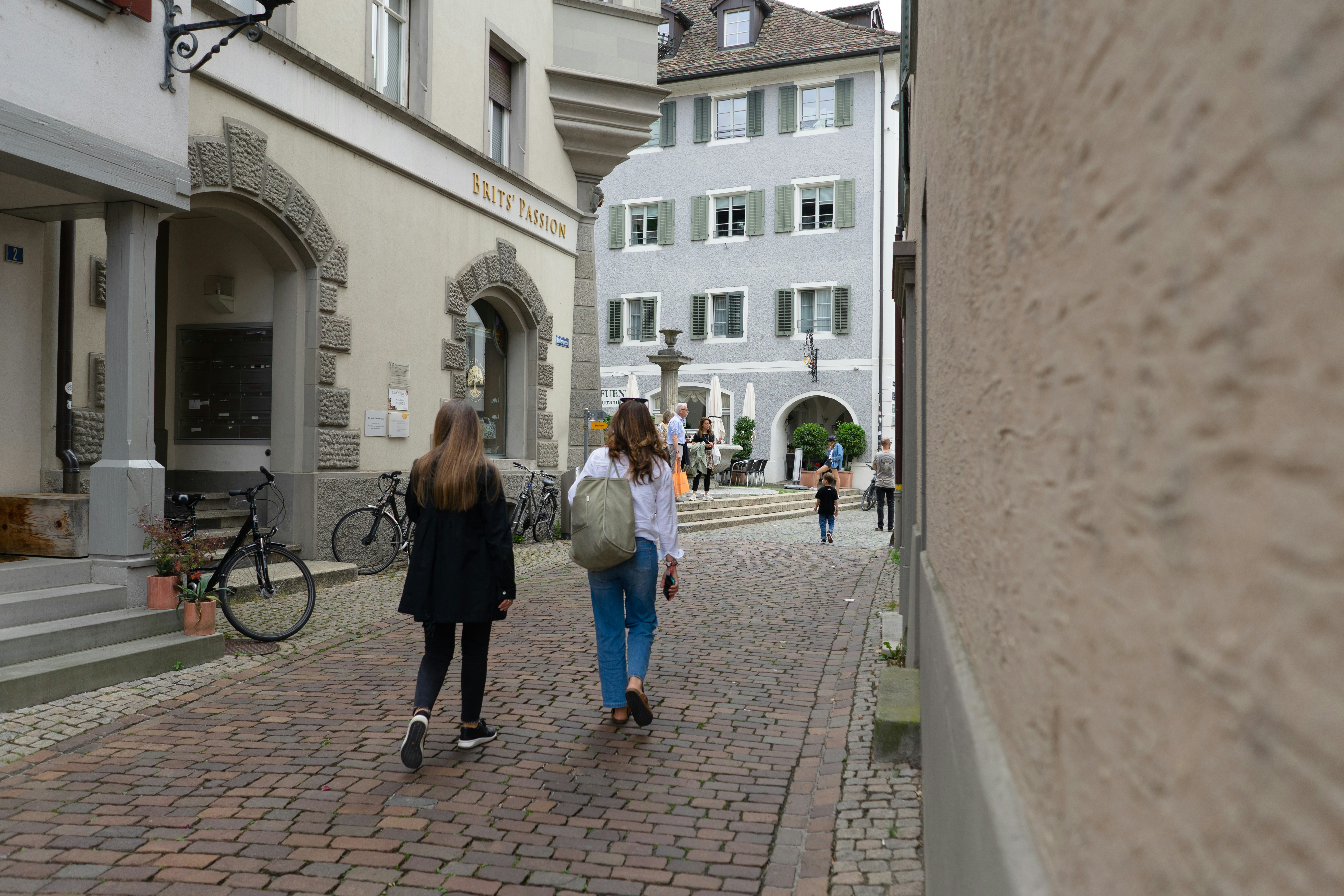 두 명의 여성이 고층 건물 옆 거리를 걷고 있습니다