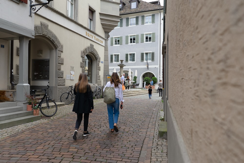 a couple of women walking down a street next to tall buildings