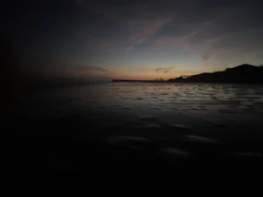 A serene beach scene with a luxury resort in the background under a matte black twilight sky