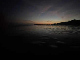 A serene beach scene with a luxury resort in the background under a matte black twilight sky