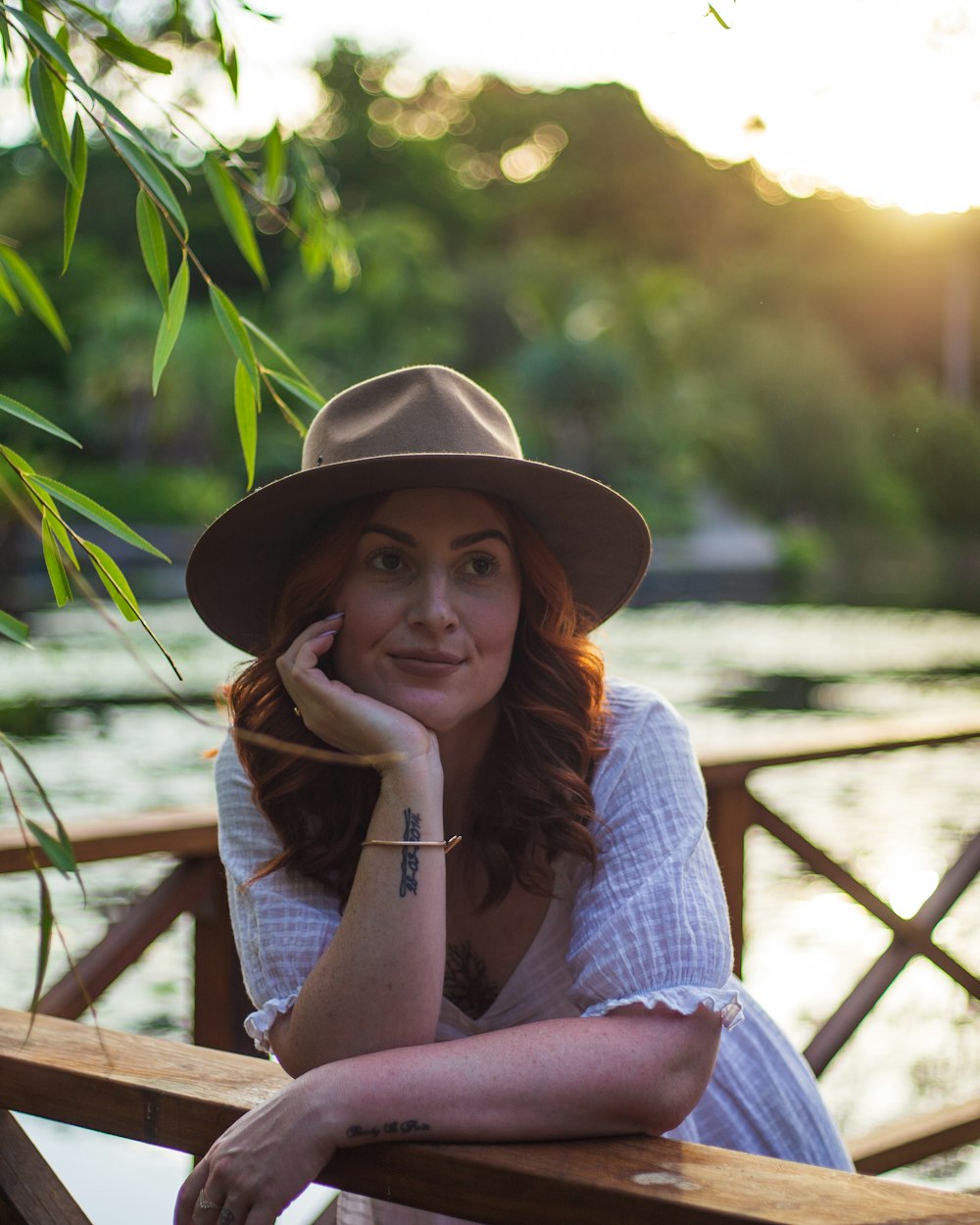 a woman wearing a hat sitting on a wooden bench