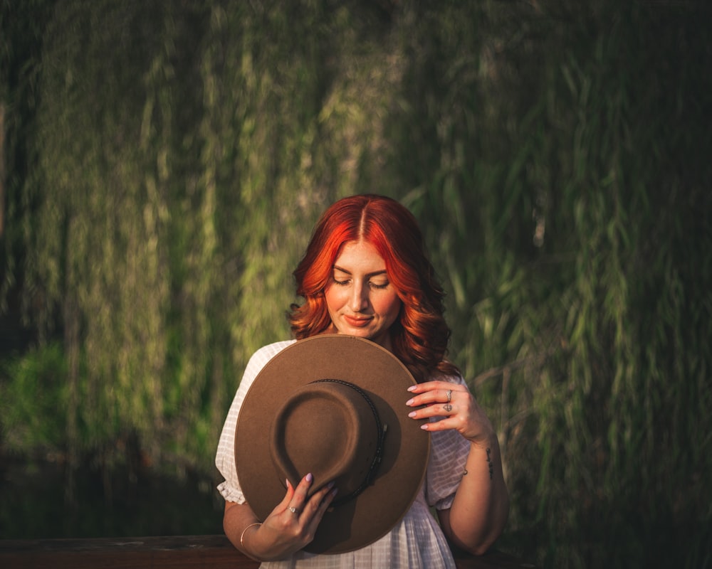 a woman with red hair is holding a hat