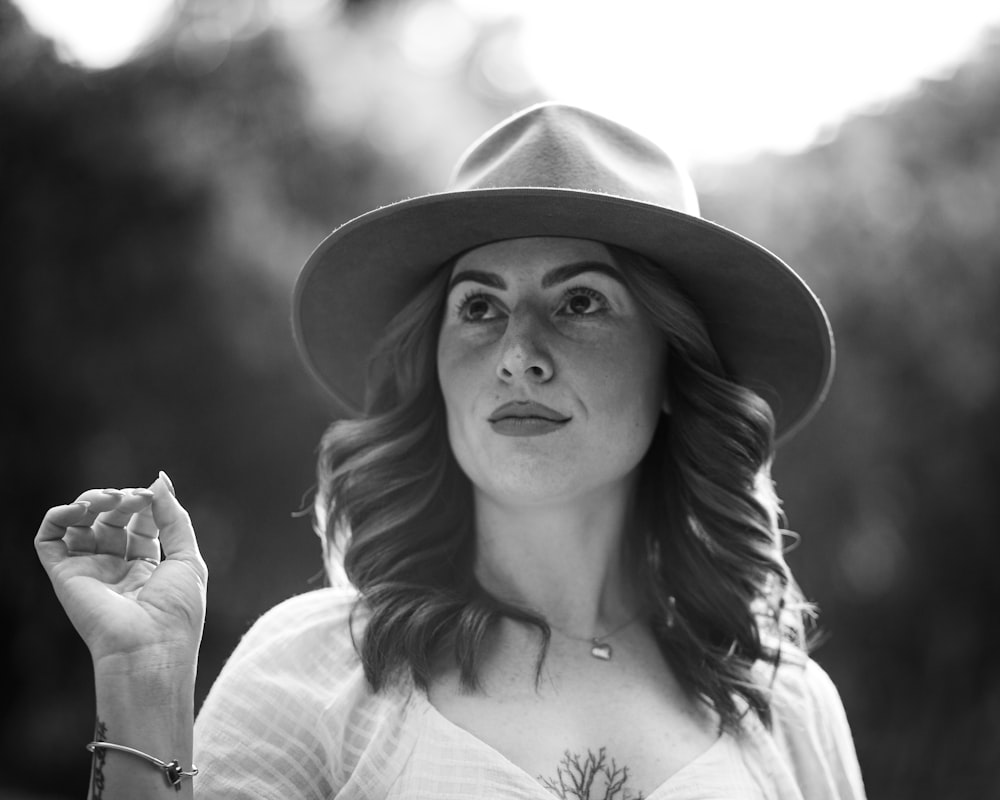 a woman wearing a hat and holding a cigarette