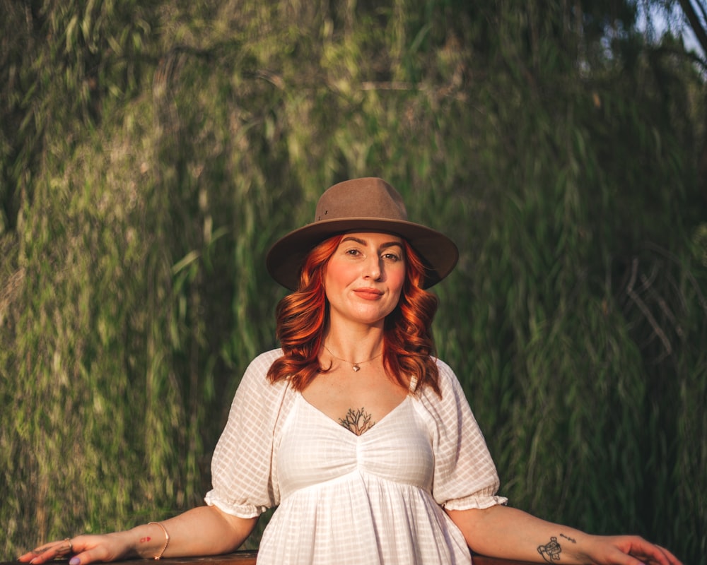 a woman with red hair wearing a white dress and a brown hat