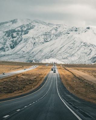 a truck driving down a road in front of a mountain