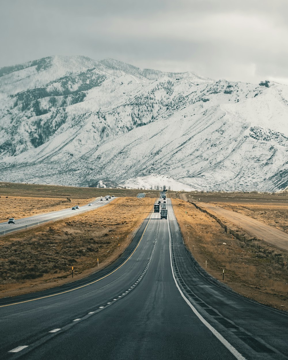 a truck driving down a road in front of a mountain