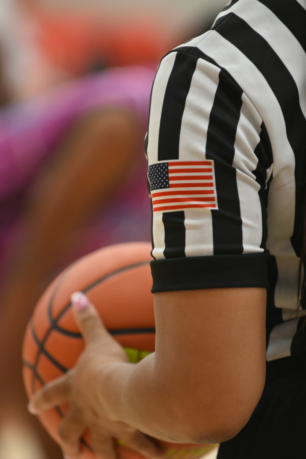 Um árbitro segurando uma bola de basquete com uma bandeira americana