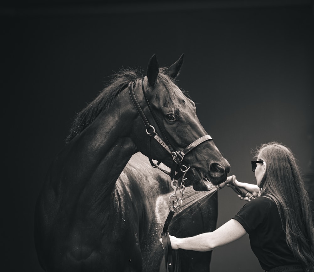 a woman standing next to a brown horse