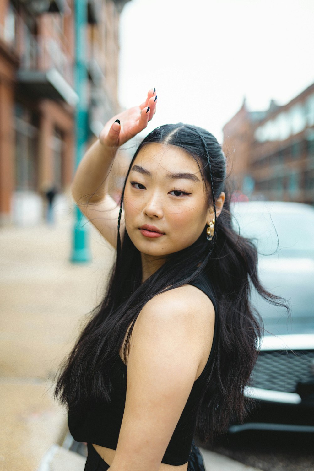 a woman in a black dress standing next to a car