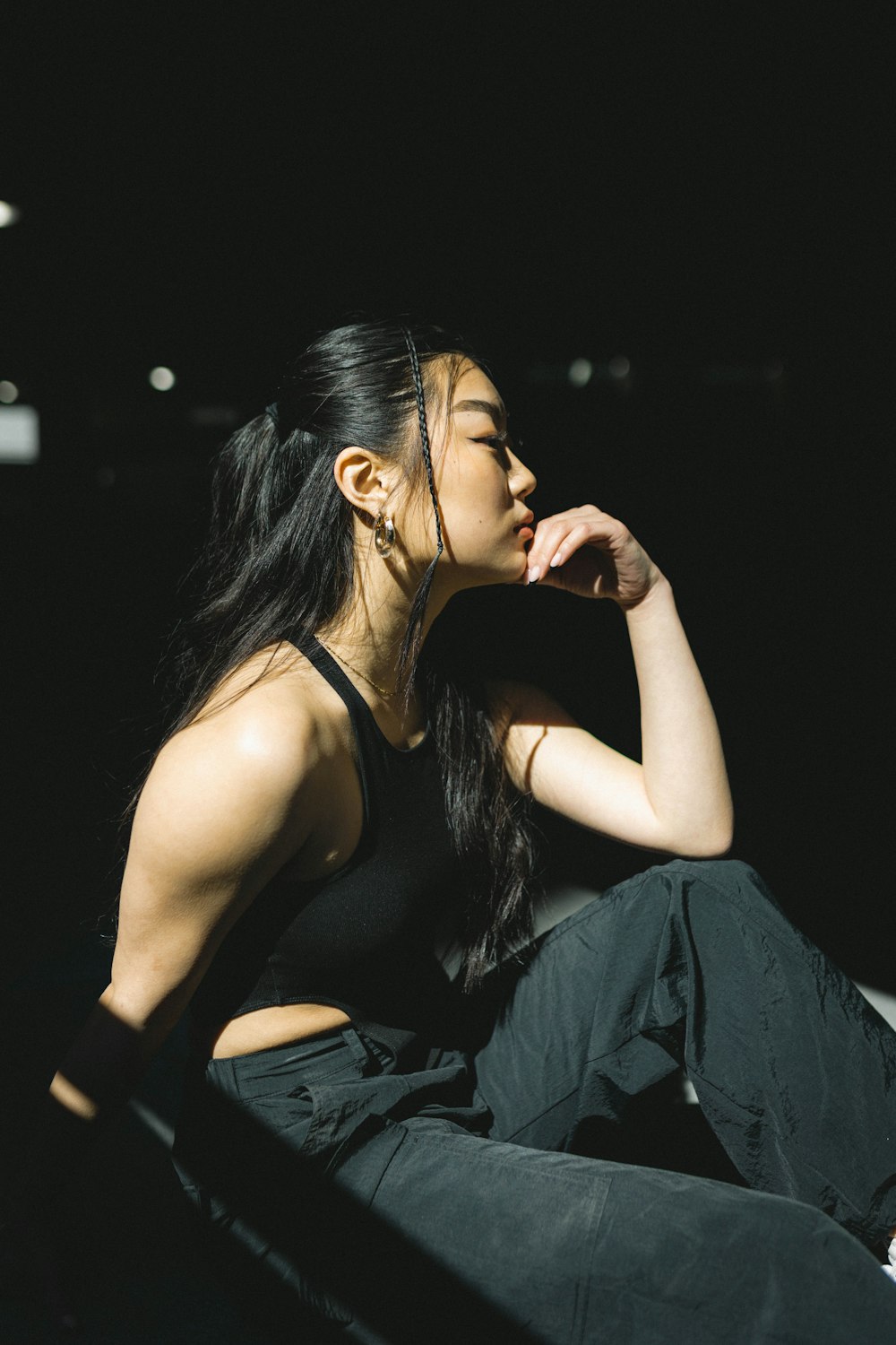 a woman sitting on the ground with her hand on her chin