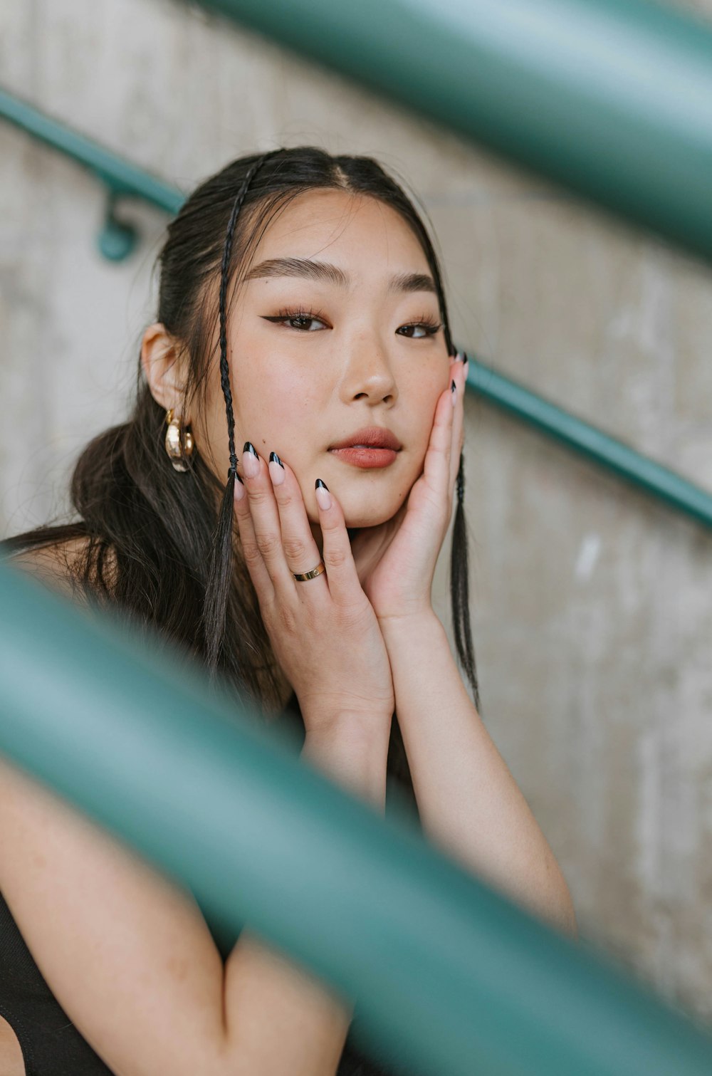 a woman with long hair and a black dress holding her hands to her face