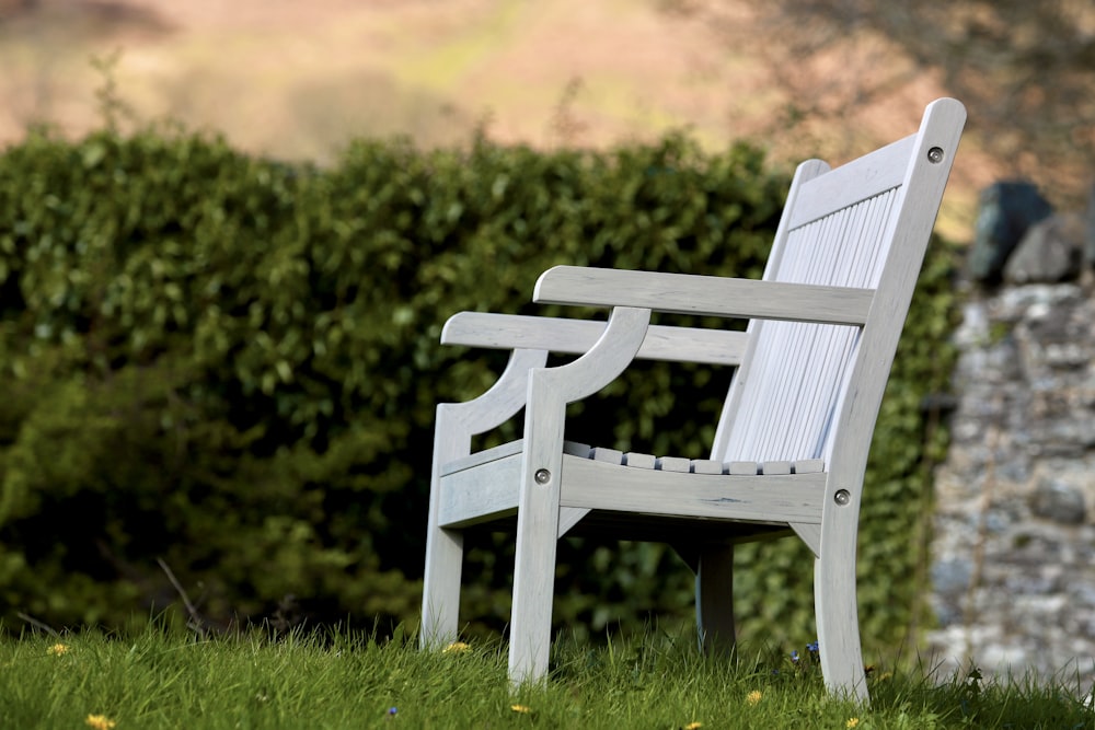 a white wooden bench sitting in the grass