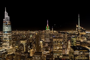 A vibrant global city skyline featuring iconic landmarks illuminated with warm red lighting under a twilight sky.